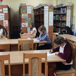 Uczniowie siedzą przy stolikach i piszą konkurs o Janie Kochanowskim.