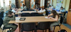 ośmioro uczniów siedzi przy stolikach i rozwiązują zadania