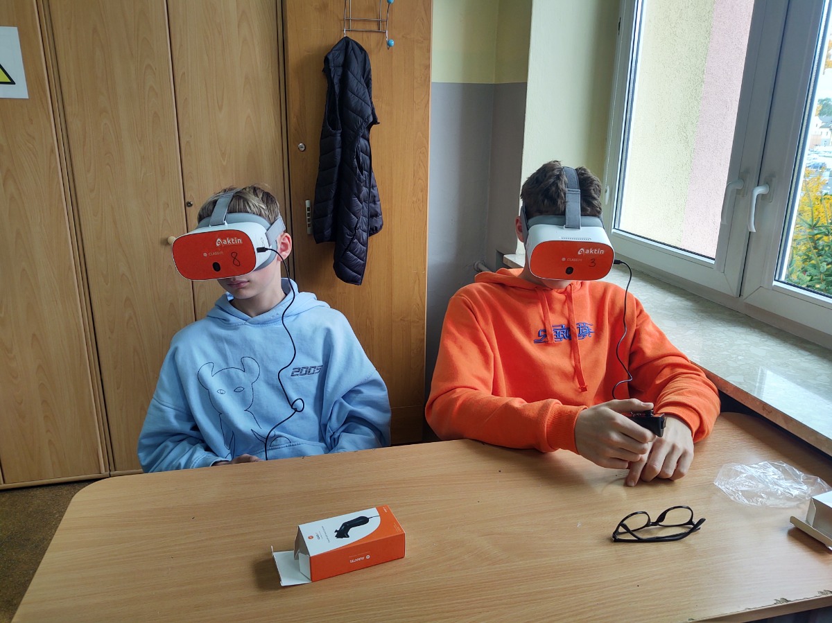 Dwoje uczniów siedzących w ławce w okularach VR