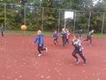 Dzieci aktywnie spędzają Dzień Chłopca. Biegają po boisku i grają w piłkę.
