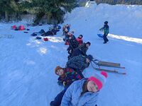 Dzieci w nartach leżą na śniegu tworząc pociąg.